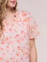 Blusa blanca de doble capa de gasa con estampado floral en tonos amarillos, celestes y rosados, escote en V con frunces y mangas cortas con volados amplios.