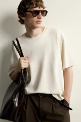 Remera de corte holgado color gris oscuro, con cuello redondo y mangas cortas. Confeccionada en tejido suave con mezcla de modal.