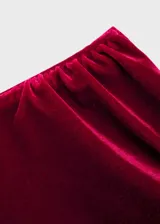 Vestido corto de terciopelo color rojo, con diseño asimétrico de un solo hombro y manga larga. Presenta un detalle de fruncido lateral que aporta un ajuste entallado a la silueta.