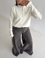 Sweater de punto color marrón chocolate, con cuello redondo y cierre frontal parcial con botones. Presenta mangas largas con puños acampanados y detalle de volados.