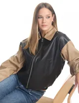 Chaqueta bomber de cuero sintético con diseño bicolor, cuerpo en color negro y mangas en color beige. Presenta cuello clásico, cierre frontal metálico y puños elásticos.