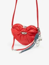 Bolso bandolera Diesel modelo Scrunch-D Heart, de color rojo y diseño en forma de corazón. Confeccionado en piel con acabado brillante y arrugado, presenta el logotipo D de metal con cristales en el centro, cierre de cremallera doble y correa ajustable.