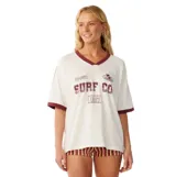 Remera Rip Curl de corte oversize color beige, con cuello en V y ribetes en color bordó en el cuello y los puños. Presenta un estampado frontal con la inscripción "Surf Co" y detalles deportivos.