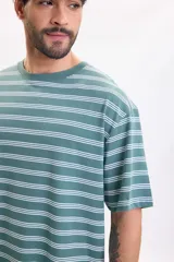 Remera manga corta de corte oversize en color verde con diseño de rayas horizontales blancas y efecto lavado.