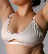 Corpiño blanco de algodón con detalle de puntilla y abertura en el centro.