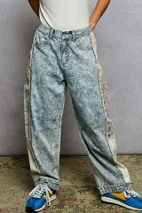Pantalon tipo barrel en denim lavado claro con efecto acid wash, corte holgado y detalles combinados en los laterales con tela a rayas y encaje.
