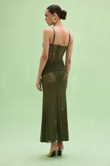 Vestido largo verde militar, sin mangas, con escote en V pronunciado, detalle de nudo en el busto y transparencias de encaje en la zona del torso y la falda.