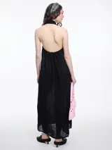 Vestido largo de lino en color azul, con cuello camisero, cierre frontal de botones y espalda descubierta con diseño estilo halter. Presenta un bordado decorativo en el cuello y bolsillos laterales.