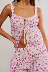 Conjunto de dos piezas de algodón con estampado floral en tonos rosados sobre base blanca, compuesto por una camisola sin mangas con escote cuadrado y lazo frontal, y pantalón largo de corte ancho.