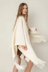 Ruana de lana color beige, tejida en punto acanalado con terminación de flecos en los bordes.