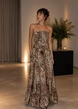 Vestido largo de silueta fluida con estampado animal print en tonos tierra. Presenta un top fruncido con tiras finas, espalda descubierta y falda amplia con volado en el ruedo.