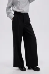 Pantalón negro de tiro alto, confeccionado en viscosa, de corte holgado y pernera ancha, con bolsillos laterales.