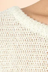 Suéter de punto color marfil con cuello barco, mangas estilo murciélago de largo tres cuartos y corte holgado. Presenta un tejido con sutiles destellos brillantes.