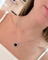Collar de cadena fina de acero con dije circular que presenta un centro de resina negra rodeado por una hilera de strass brillante.