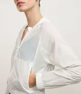 Campera rompevientos deportiva cropped de color blanco, con capucha, cierre frontal y puños elásticos. Confeccionada en poliamida, presenta un diseño ligero y funcional.
