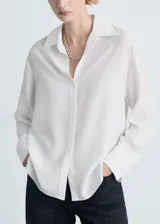 Camisa de corte recto confeccionada en tejido fluido de lyocell, con cuello camisero, cierre frontal de botones, mangas largas con puños abotonados y aberturas laterales.
