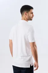 Remera polo de piqué manga corta, color blanco con estampado geométrico sutil. Presenta cuello camisero y cartera con dos botones oscuros.
