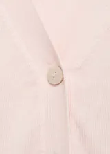Cardigan de punto fino en color rosa claro, con cuello en pico, cierre frontal de botones y manga larga con puños acanalados.