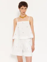 Short blanco de poplín con cintura elastizada y cordón para anudar. Presenta piedras al tono en el delantero y la espalda, y recortes de tela complemento en el ruedo y aberturas laterales.