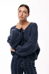 Saco tejido de punto color azul, con escote en V y cierre frontal mediante lazos. Presenta mangas largas amplias con puños ajustados y un calce relajado.