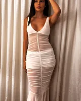 Vestido largo de color negro con escote en V y sin mangas. Presenta un diseño entallado con drapeados de tela translúcida que generan texturas y transparencias. Incluye espalda descubierta y detalles de lentejuelas en la cadera.