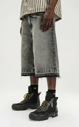 Bermuda de denim en color negro con efecto lavado, corte oversize y ruedo desflecado. Incluye un cinturón fino integrado en la cintura.