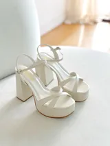 Sandalias de cuero sintético color manteca, con plataforma y tacón bloque. Presentan tiras cruzadas en el empeine y pulsera con hebilla al tobillo.