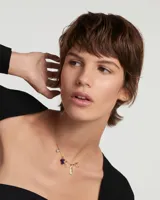 Dije colgante dorado con forma de corazón atravesado por una flecha, con incrustaciones de circonitas blancas.