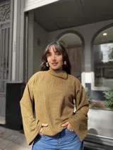 Polera de punto color ocre con diseño acanalado, cuello alto con abertura lateral y mangas amplias de corte recto.