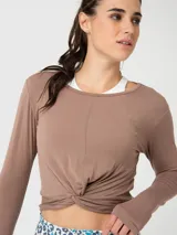 Polera de manga larga color canela, confeccionada en modal, con diseño de nudo frontal y aberturas para los pulgares en los puños.