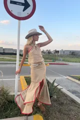 Falda midi color beige confeccionada en lino, con corte irregular, volados y ribete rojo.