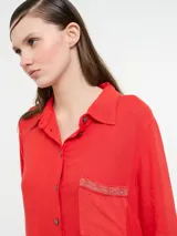 Vestido camisero largo color rojo, confeccionado en lino y viscosa, con cartera de botones delanteros centrales y bolsillo delantero superior con terminación de galón metalizado.