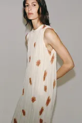 Vestido midi de viscosa color blanco con estampado abstracto marrón, diseño sin mangas, cuello redondo plisado y cierre de lazos en la espalda.