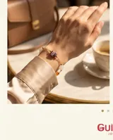 Pulsera de cadena fina con baño de oro, adornada con piedras naturales de diversos colores y formas, incluyendo tonos violeta, blanco y naranja.