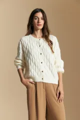 Cardigan de punto color terracota con diseño de trenzas verticales, cuello redondo y cierre frontal con botones metálicos. Presenta mangas largas con puños ajustados y un calce holgado.