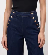 Pantalón wide leg de jean azul oscuro, de talle alto con calce amplio y detalles de botones dorados en el lateral frontal.