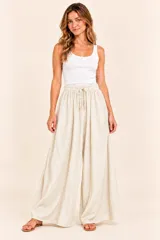 Pantalón ancho color beige, con cintura elástica fruncida y cordón ajustable.