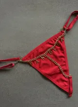 Tanga roja con tiras regulables y detalle de cadena dorada colgante con letras que forman la palabra "BANDIDA".