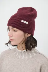 Gorro de punto ribb color bordó con vuelta y pequeña etiqueta blanca con la inscripción "Autumn.".