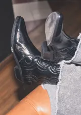 Bota corta tipo texana en cuero acharolado con punta afinada y taco bajo.