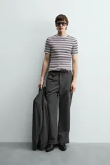 Camiseta de punto canalé slim fit, con cuello redondo y manga corta. Presenta un estampado de rayas horizontales en blanco, negro y rosado.