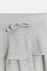 Minifalda gris melange de tiro medio, confeccionada en mezcla de algodón, con cintura elástica ajustable con cordones y diseño de doble volante en el bajo.
