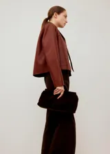 Chaqueta corta color bordó, de manga larga, con cuello camisero, bolsillos frontales con solapa y cierre de botones oscuros.
