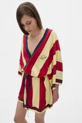 Bata tipo kimono a la rodilla, con rayas verticales rojas y amarillas y cuello en V azul marino. Tiene un logo bordado en el pecho y un lazo en la cintura.