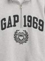 Buzo deportivo de color rosado con cuello alto y medio cierre frontal. Presenta el logo de la marca Gap 1969 bordado en el pecho junto a un emblema circular. Posee mangas largas con puños elásticos y un corte holgado.