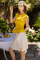 Minifalda color crudo de lino natural, con cintura elastizada en la espalda, cinto decorativo y tablas laterales que aportan movimiento y volumen.