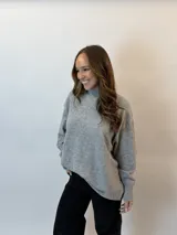 Buzo gris melange de tejido de punto, con cuello alto redondo, mangas largas y corte holgado.
