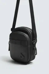 Bandolera vertical negra con acabado engomado, compartimento principal con cierre de cremallera y bolsillo interior plano. Bolsillo frontal con cierre de cremallera. Asa de hombro ajustable y extraíble.