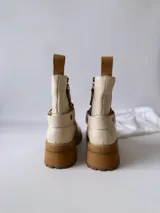 Botas cortas color crudo de cuero, con cierre lateral, pulsera desmontable y suela marrón.