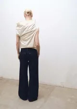 Pantalón de jean estilo wide leg en color azul oscuro, con tiro medio, detalle de pinzas en la cintura, cierre frontal con cremallera y botón, y bolsillos laterales.